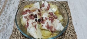 Lubina pescado en el horno con patatas, cebolla, pasas y jamón.