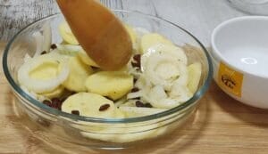 Lubina pescado en el horno con patatas, cebolla, pasas y jamón.